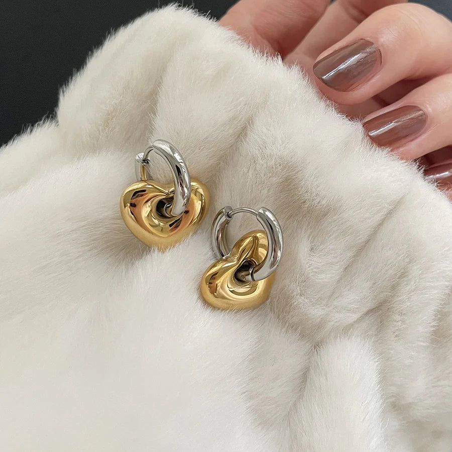 Gold and silver hoop earrings on a white fur surface