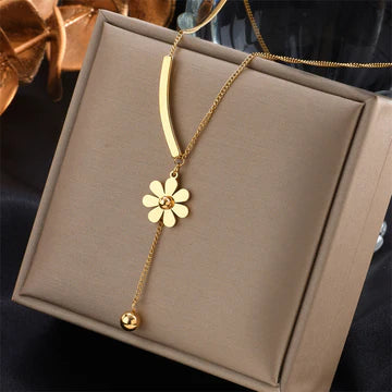 Gold necklace with a flower pendant on a brown jewelry box