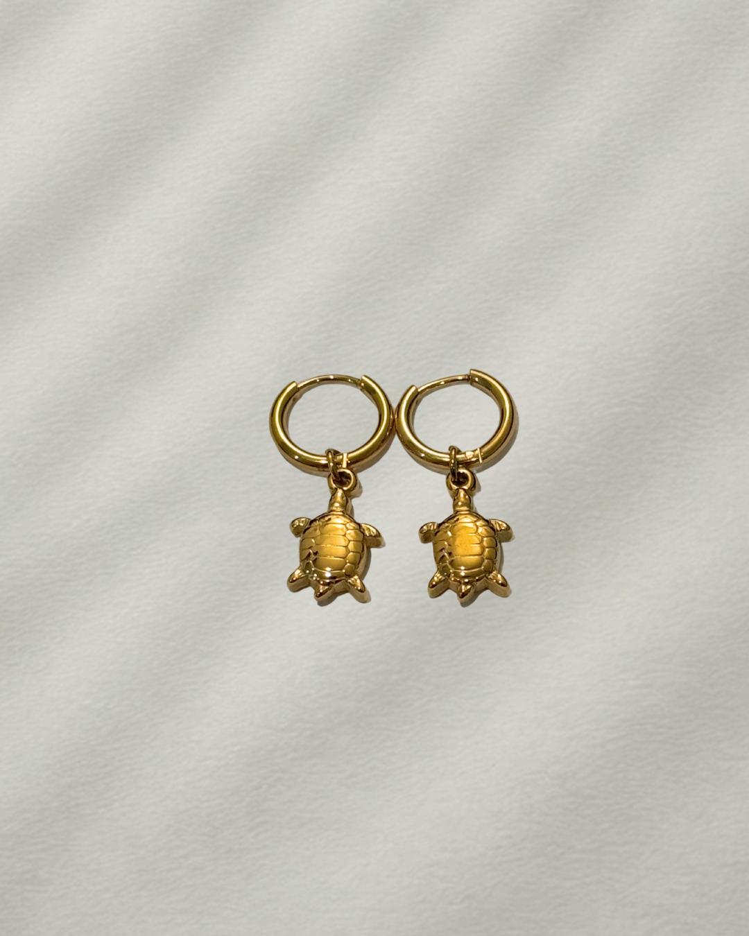 Gold turtle earrings on a light gray background