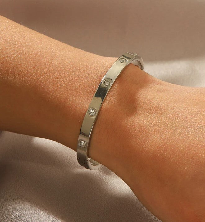 Silver bracelet with small stones on a wrist against a neutral background