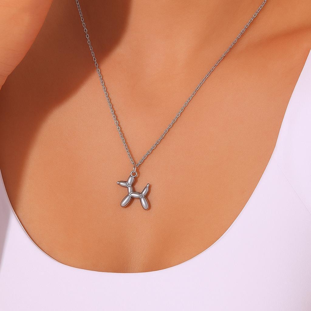 Silver balloon dog necklace on a person wearing a white top